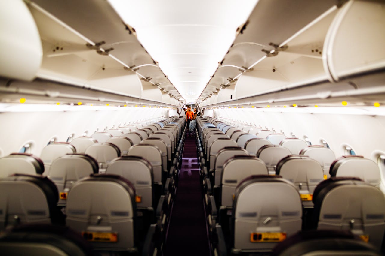 View of an empty airplane interior with aisle seats and overhead bins.